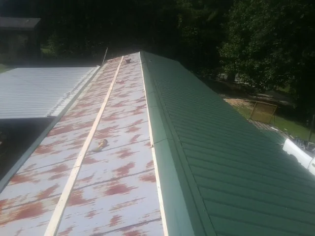 Old rusted panels beside newly installed green metal roofing — Wind Damage Roof Repair by Roofing Brothers in Overpeck