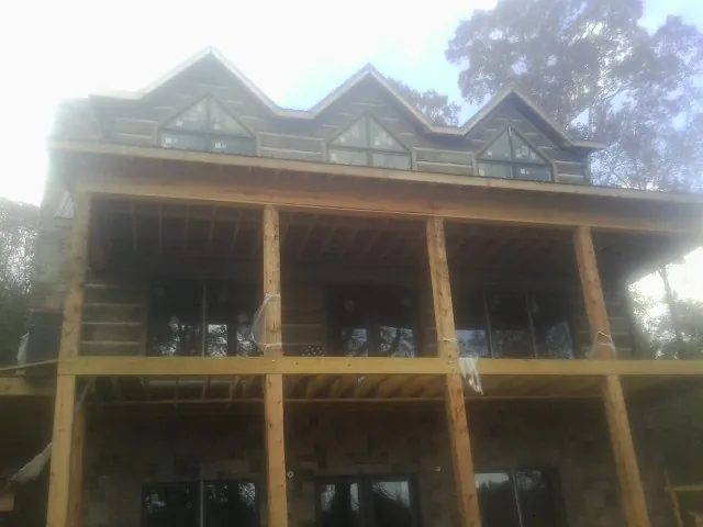 Dormers and porch framing on a large log home under construction — Roof Coating work by our crew in Overpeck
