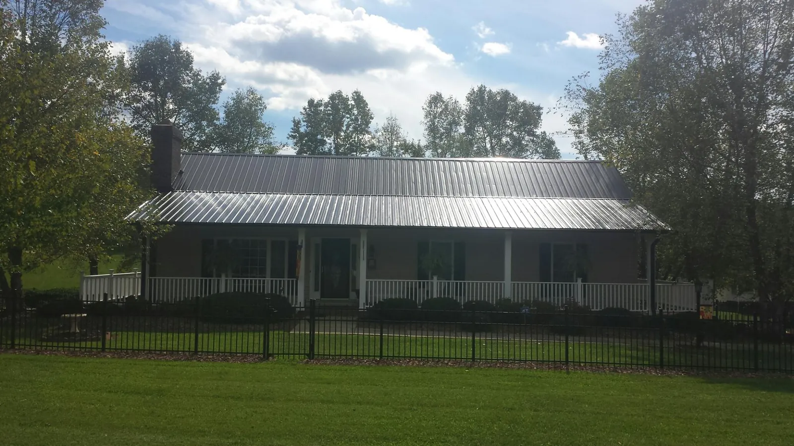 Gray metal roof on a brick ranch with a full width front porch — Gutter Guard Installation work by our crew in Overpeck