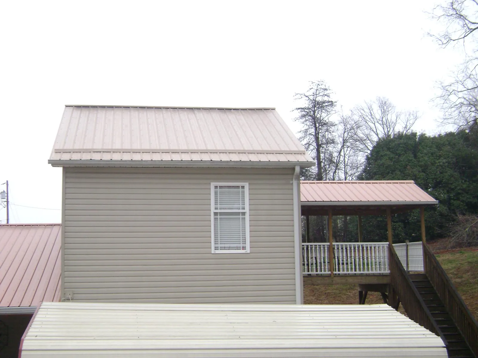 Tan metal roofs on a two story addition and attached porch, from a Roof Replacement job in Overpeck