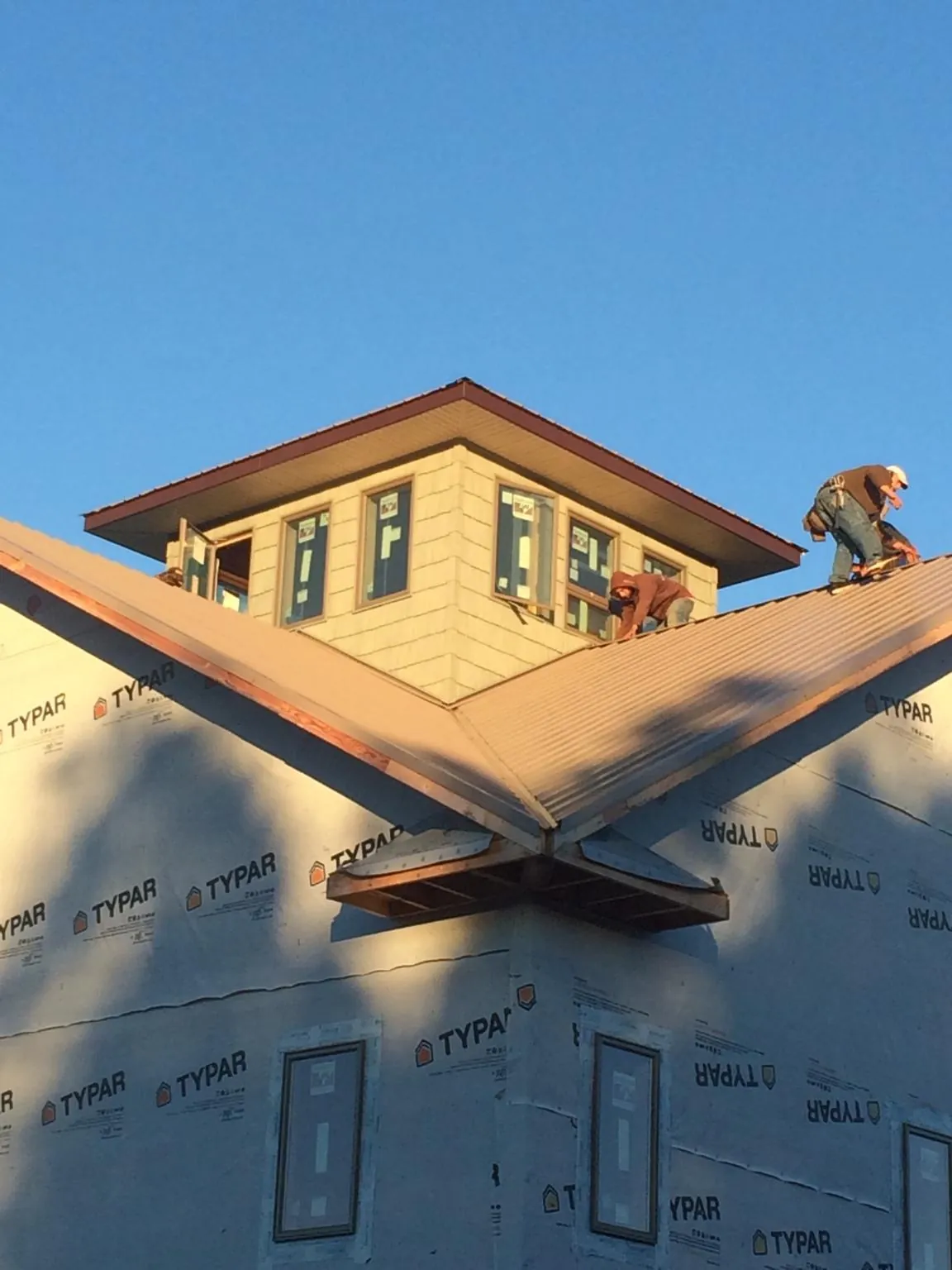 Roofers working around a rooftop cupola on a new metal roof at sunset — Roof Waterproofing in Overpeck by Roofing Brothers